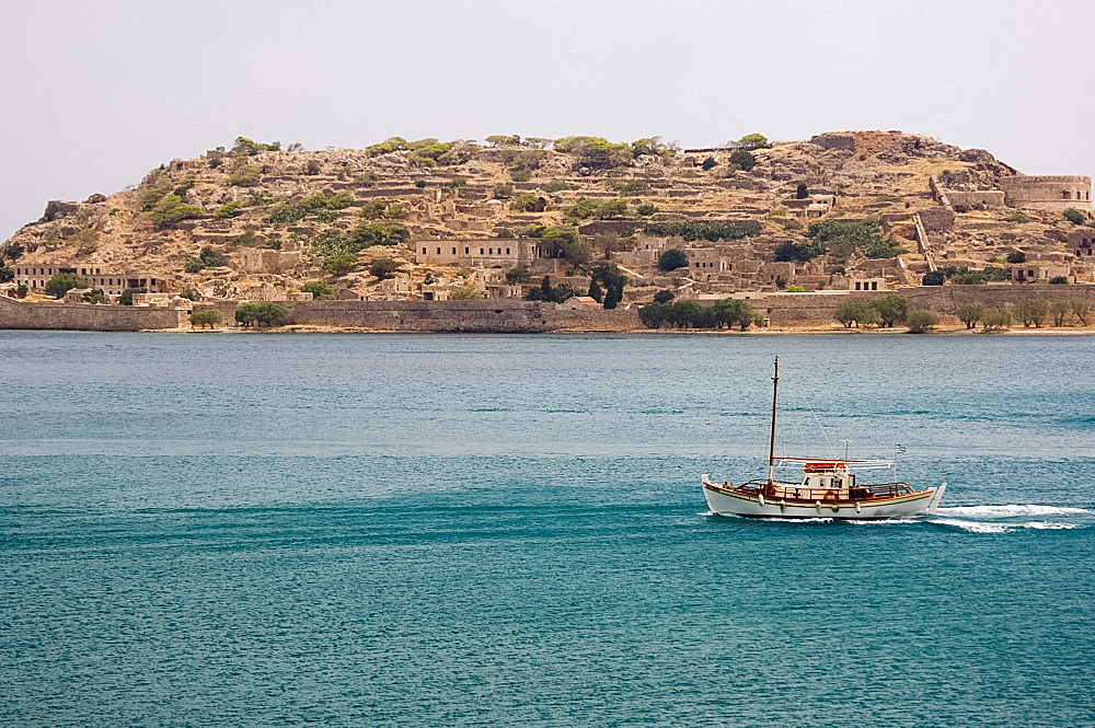 A small boat passing the island of Spina Longa, Crete, Greece, Europe