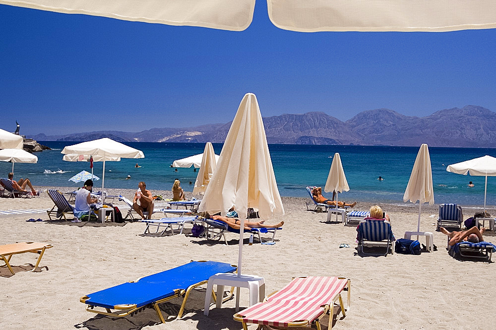 Umbrellas on the beach at Kitroplatia, a small cove outside Agios Nikolaos, Crete, Greek Islands, Greece, Europe