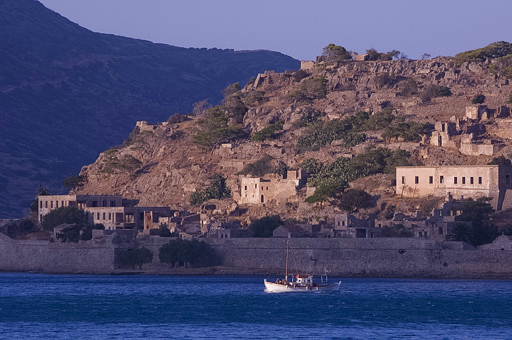 A small boat passing the island of Spina Longa, Crete, Greek Islands, Greece, Europe