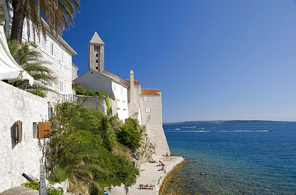 Swimmers and sunbathers on rock wall next to Rab Town, island of Rab, Kvarner region, Croatia, Europe