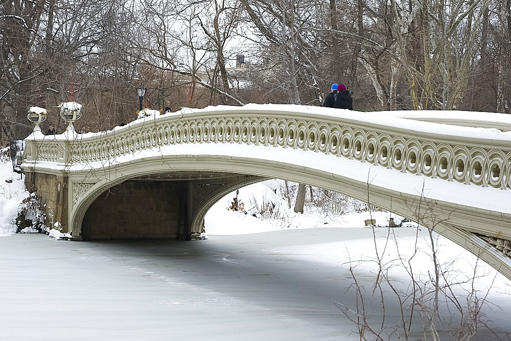 People walking across the Bow Bridge in Central Park after a snowstorm, New York City, New York State, United States of America