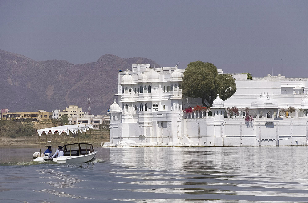 A small boat heading toward the Lake Palace Hotel on Lake Pichola in Udaipur, Rajasthan, India, Asia