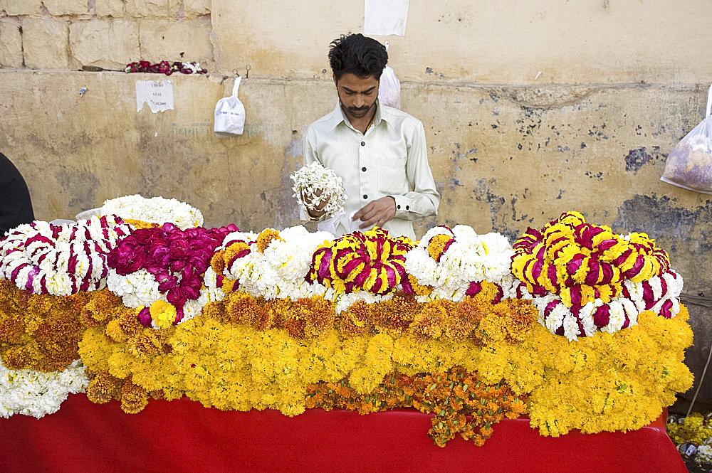 A man selling garlands of flowers outside a temple in Jaipur, Rajasthan, India, Asia