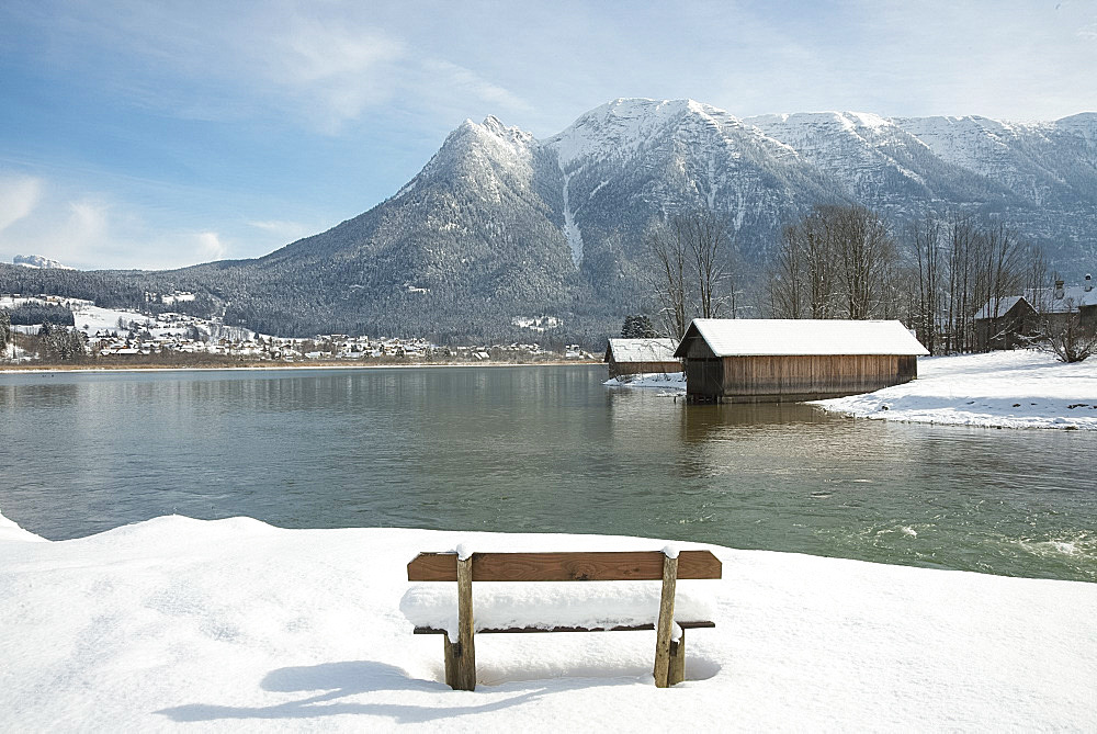 A snow covered bench facing Hallstatter See and the surrounding mountains near the town of Hallstatt, Austria, Europe