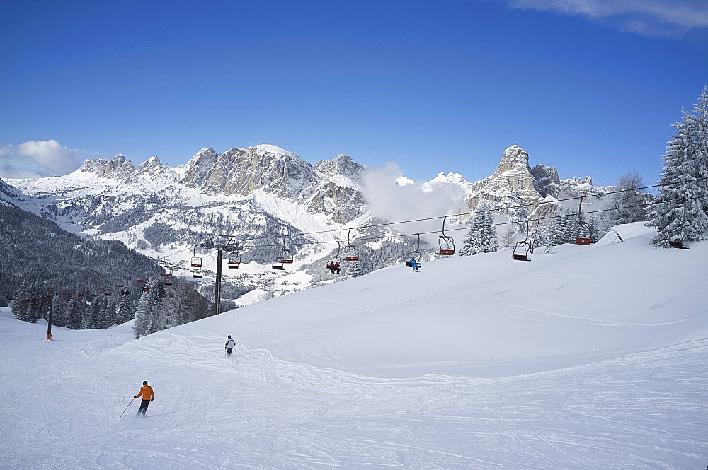 Skiers at the Alta Badia ski resort with Sassongher Mountain in the distance, Dolomites, South Tyrol, Italy, Europe