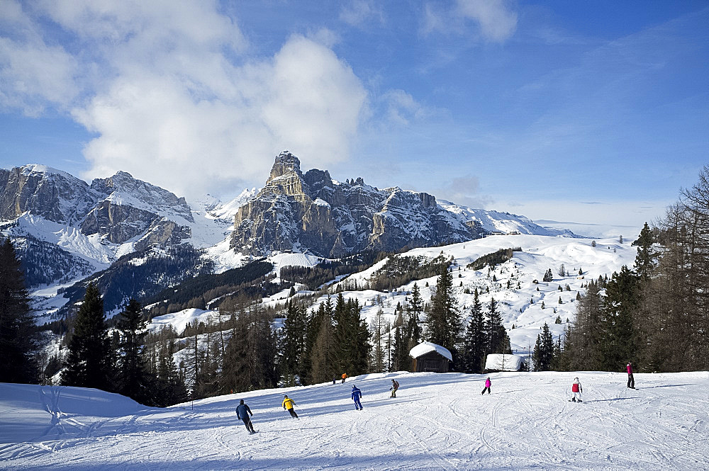 Skiers at the Alta Badia ski resort with Sassongher Mountain in the distance, Dolomites, South Tyrol, Italy, Europe