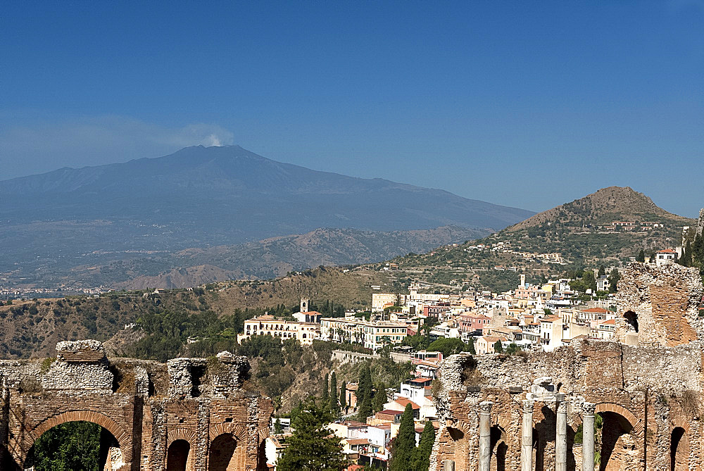 A view of Taormina from the Greek Theatre and Mount Etna smoking in the background, Taormina, Sicily, Italy, Europe