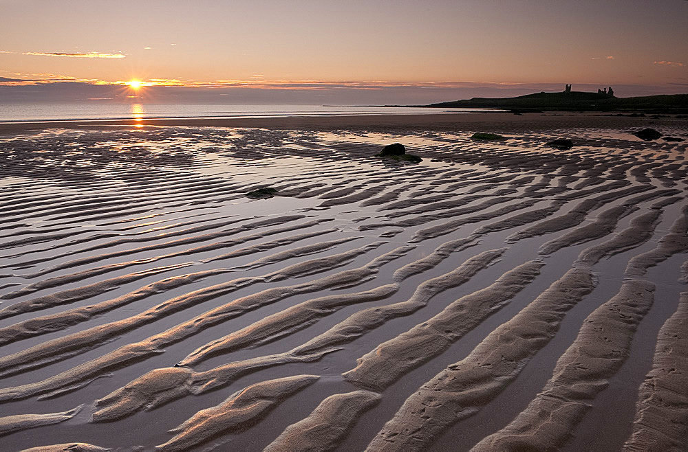 Ripples of sand near Dunstanburgh Castle in Embleton Bay at sunrise, Northumberland, England, United Kingdom, Europe