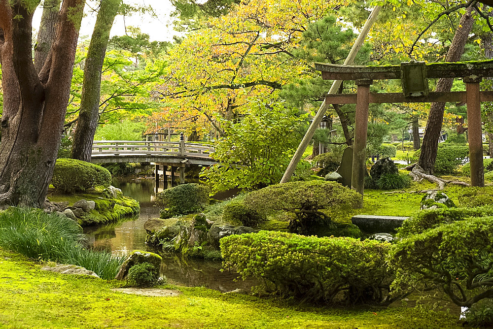 Hanambashi Bridge and a stone gate surrounded by autumn foliage in the Kenrokuen Garden, Kanazawa, Ishigawa, Japan, Asia