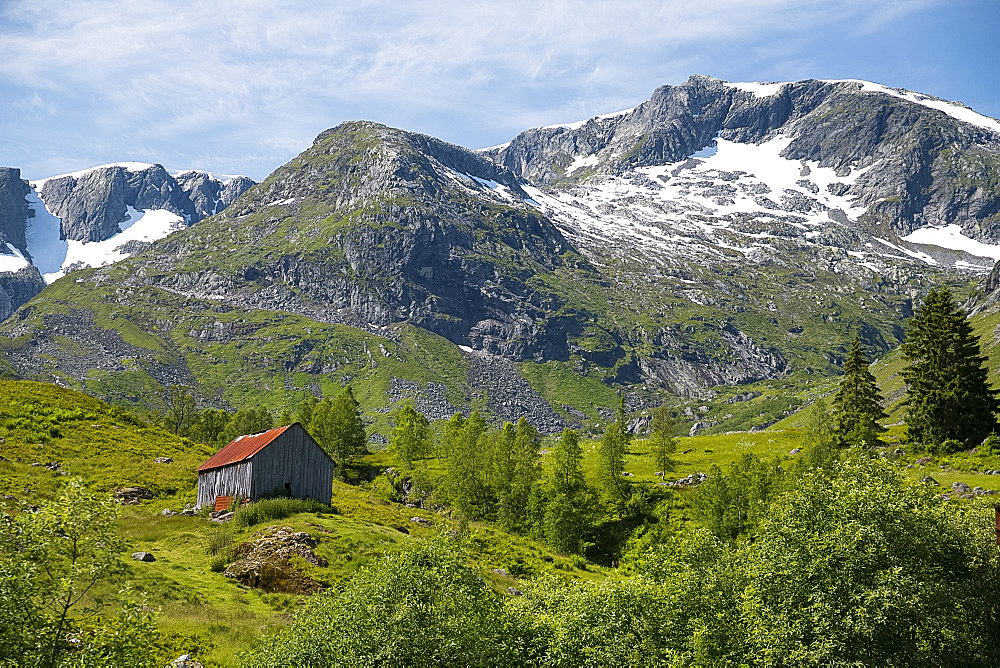 A wooden barn on a hillside below the Frudalsbreen Glacier, Vestlandet, Norway, Scandinavia, Europe