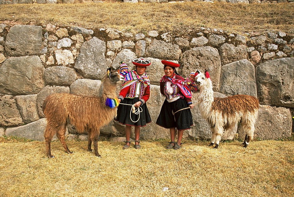 Local women and llamas in front of Inca ruins, near Cuzco, Peru, South America