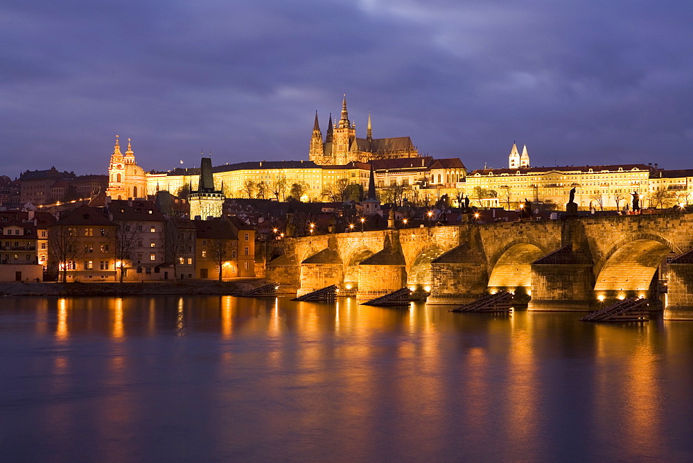 St. Vitus Cathedral, Charles Bridge and the Castle District illuminated at night in winter, seen from across the Vltava River, Prague, Czech Republic, Europe