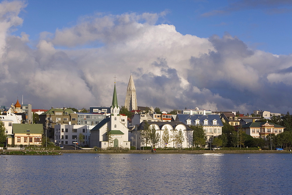 The tin-clad Frikirkjan i Reykjavik church and Hallgrimskirkja rising above the city viewed across Lake Tjorn, Reykjavik, Iceland, Polar Regions