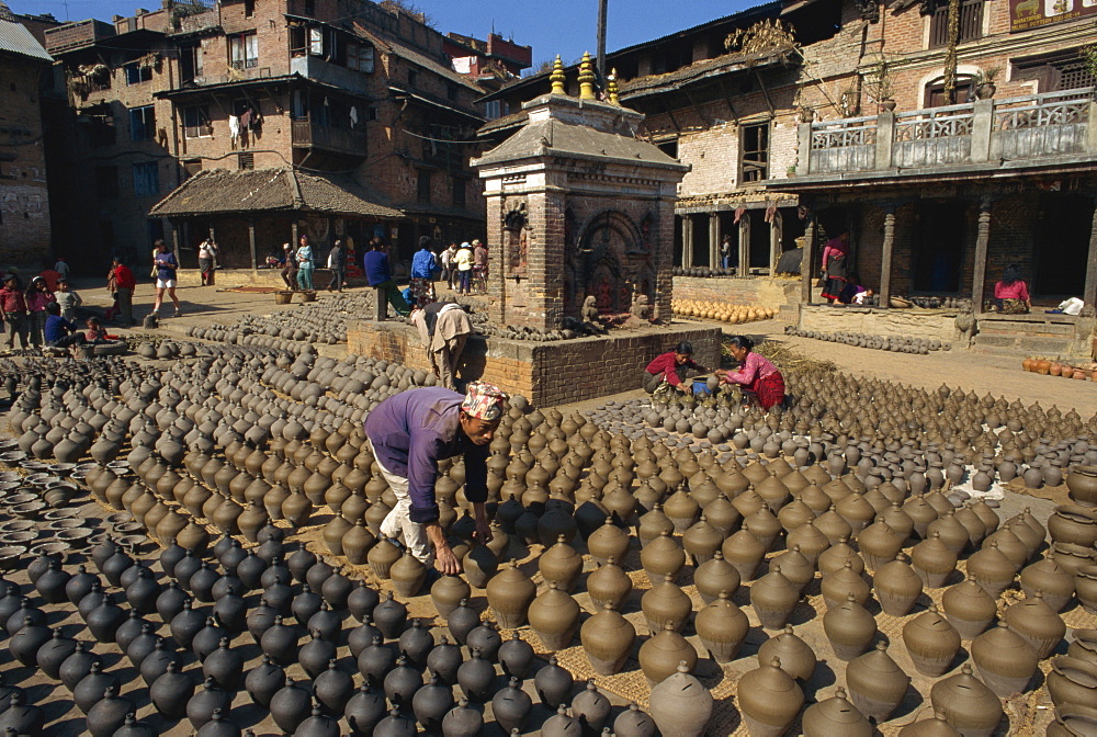 Man with rows of clay pots drying in Potters Square at Bhaktapur near Kathmandu, Nepal, Asia