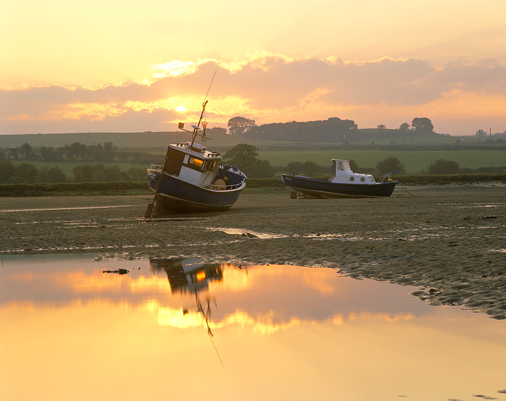 Fishing boat at sunset on the Aln estuary at low tide, Alnmouth, Northumberland, England, United Kingdom, Europe