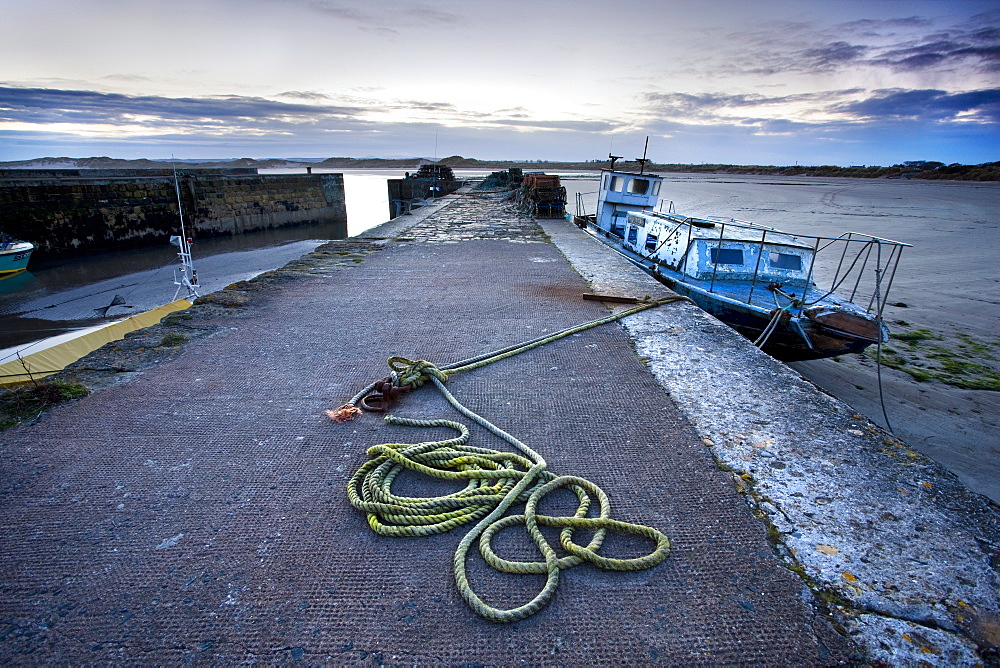 Beadnell Harbour at dusk showing old rope coiled on harbourside and dilapidated fishing boat, Beadnell, Northumberland, England, United Kingdom, Europe