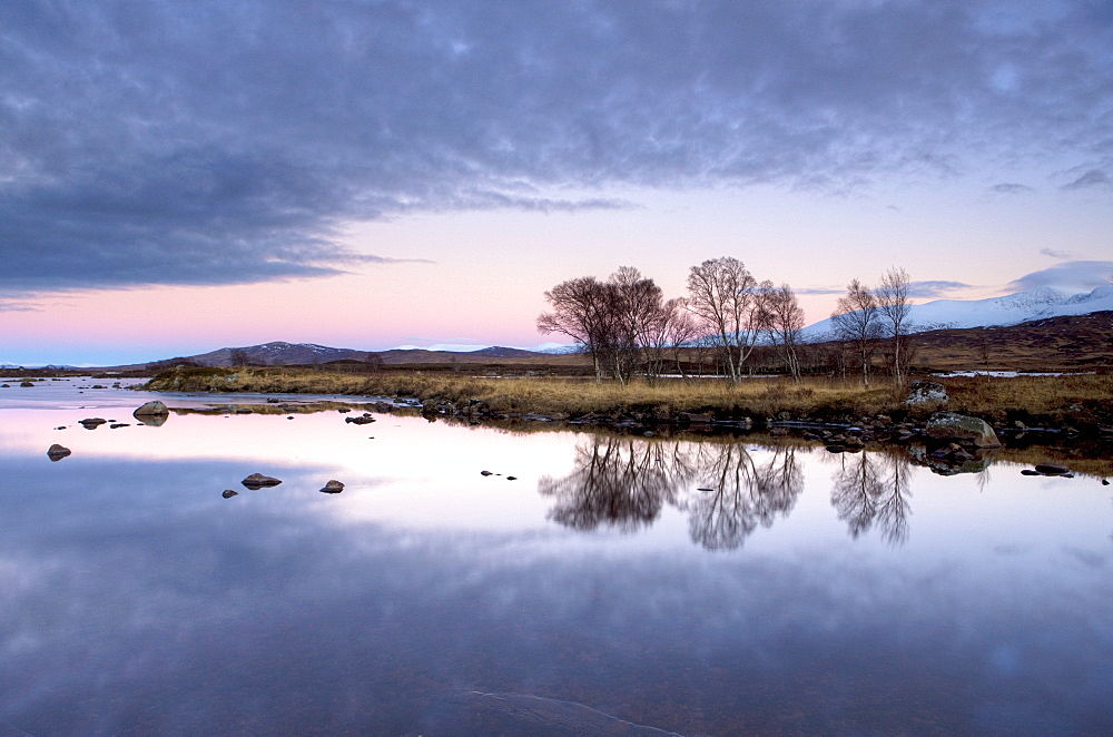 Evening view over flat calm Loch Ba with pink afterglow in sky, reflected in loch and snow-capped mountains in distance, Rannoch Moor, near Fort William, Highland, Scotland, United Kingdom, Europe