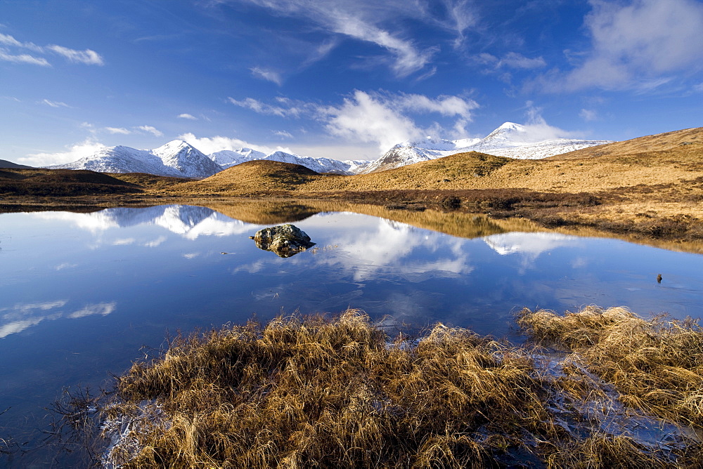 Black Mount Hills covered in snow on a sunny winter's day with reflections in a frozen Lochain, Rannoch Moor, Highland, Scotland, United Kingdom, Europe