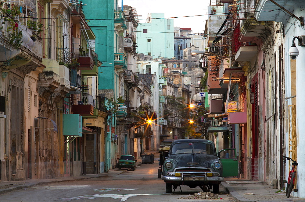 Street scene before sunrise showing dilapidated buildings crowded together and vintage American cars, Havana Centro, Havana, Cuba, West Indies, Caribbean, Central America