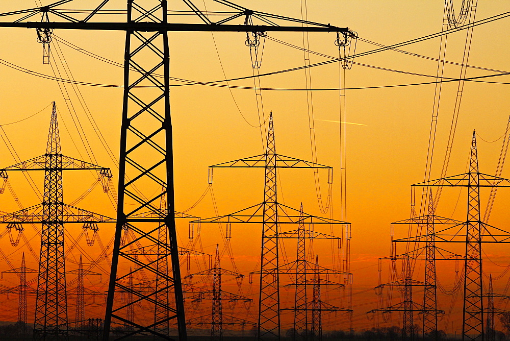 Pylons and power lines in morning light, Germany, Europe