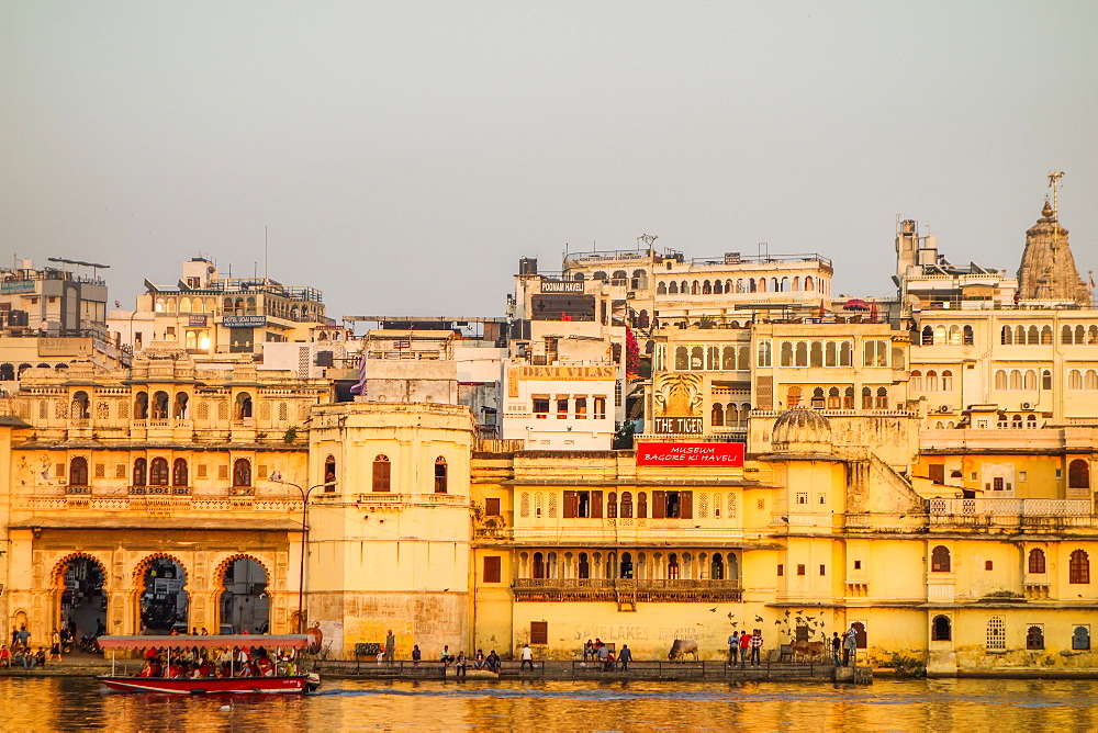 Old building facades, boat in foreground, City Palace side, Lake Pichola, Udaipur, Rajasthan, India, Asia