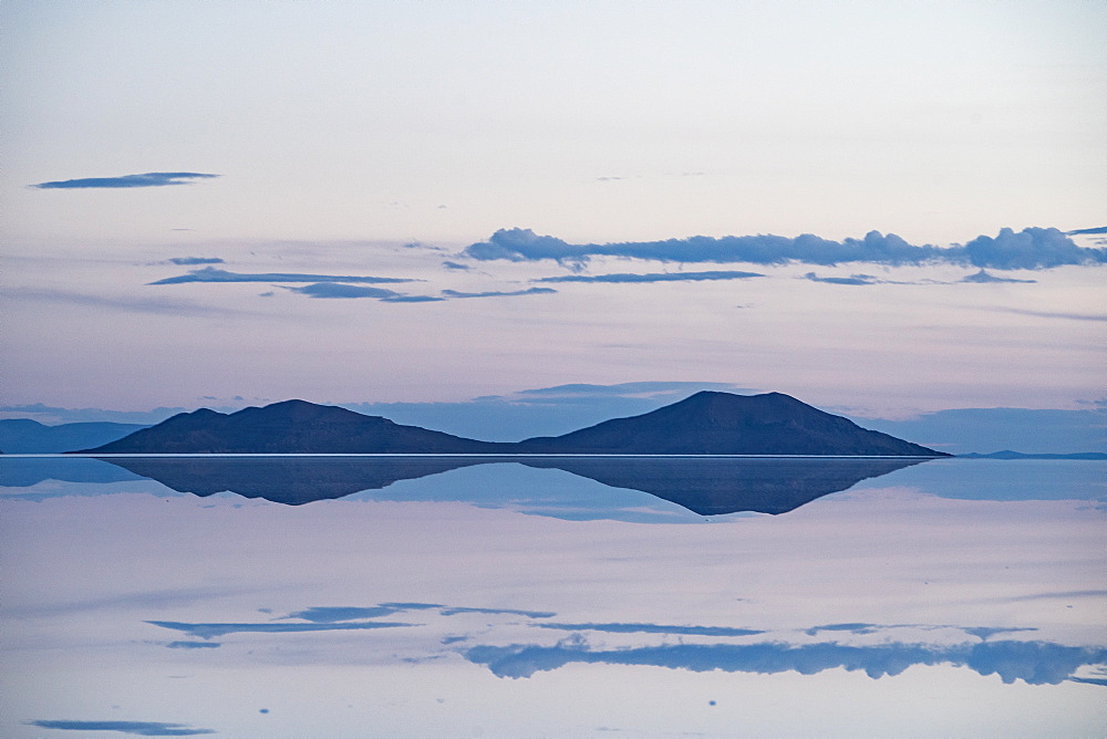 Pastel-coloured beauty of salt flats reflecting the clouds and mountains after rainfall just after sunset, Uyuni, Bolivia, South America