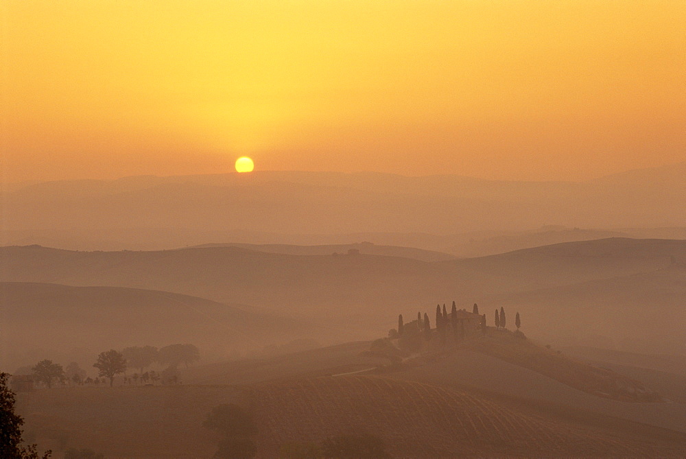 Landscape of fields and cypress trees at sunset in the hills of Tuscany, Italy 