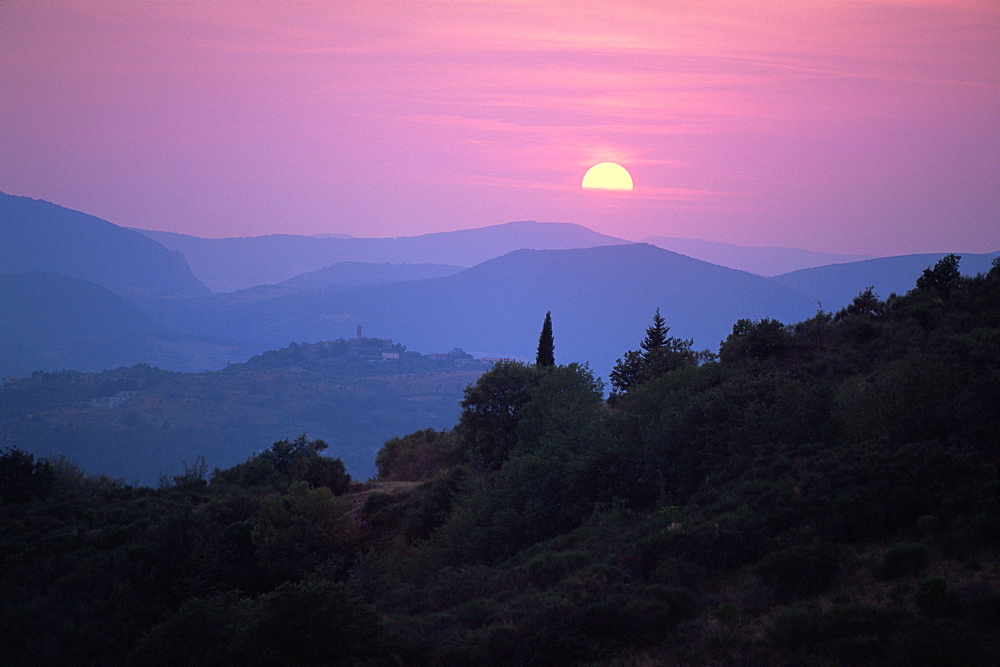 View of Tuscan hill top town with setting sun, Tuscany, Italy, Europe