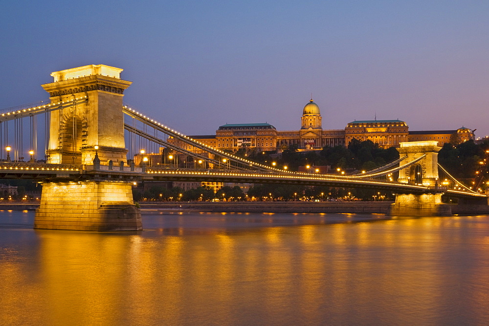 The Chain Bridge (Szechenyi Lanchid), over the River Danube, illuminated at sunset with the Hungarian National Gallery behind, UNESCO World Heritage Site, Budapest, Hungary, Europe