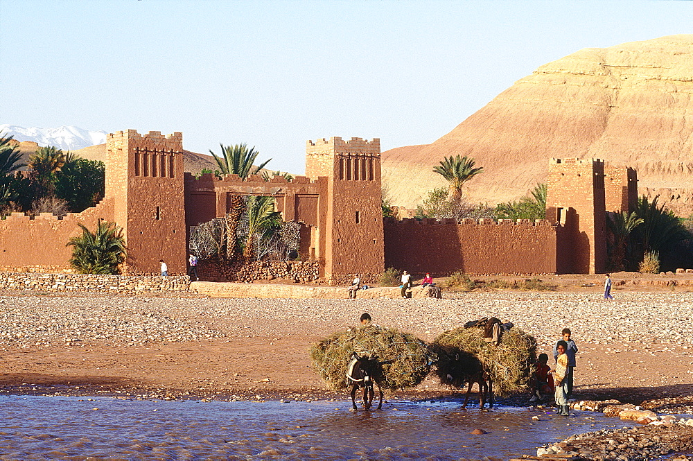 Morocco, South, Ouarzazate Region, Ait Benhaddu Ksar Ruins (Ancient Adobe Fortress And Village), Overview On The Ramparts And River (Oued), Peasants Crossing On Donkey)