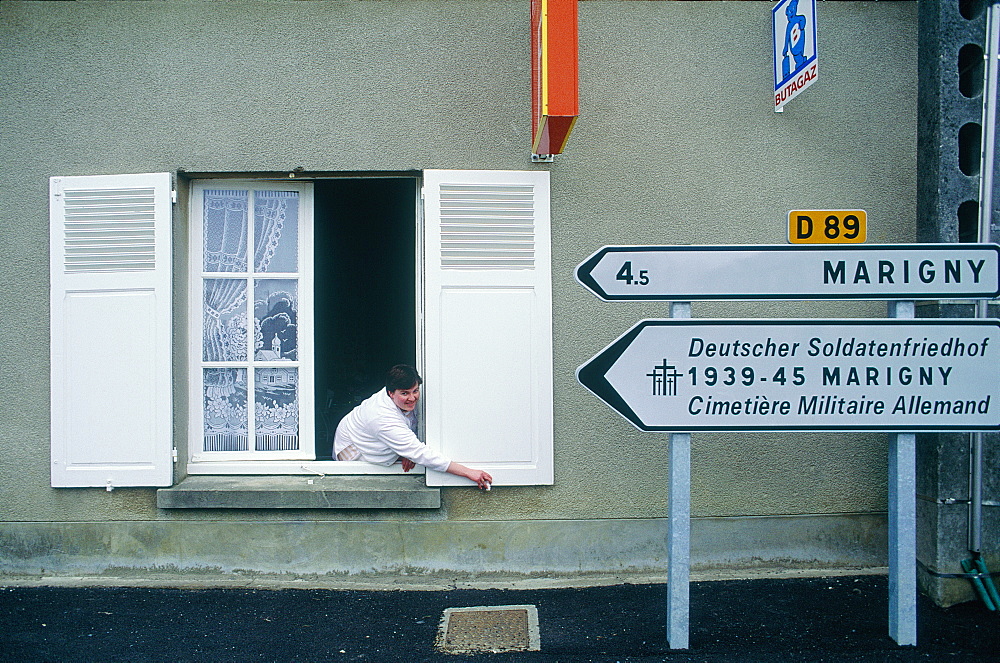 France, Normandy, Manche (50), La Chapelleenjuger, Woman Opening Her Shutters, Road Signs Along Her House Facade