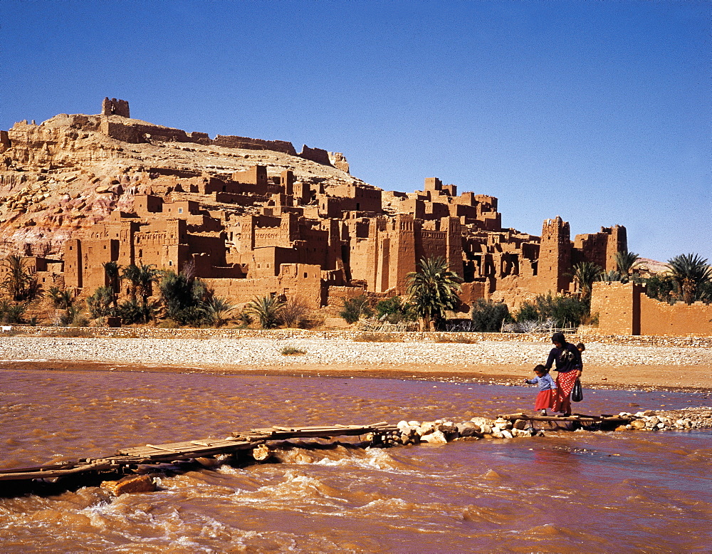 Morocco, Ouarzazate Region, Ait Ben Haddou Kasbah (Mud Fortress) At Spring, Fellah (Peasant) And Child Crossing The Oued (River)