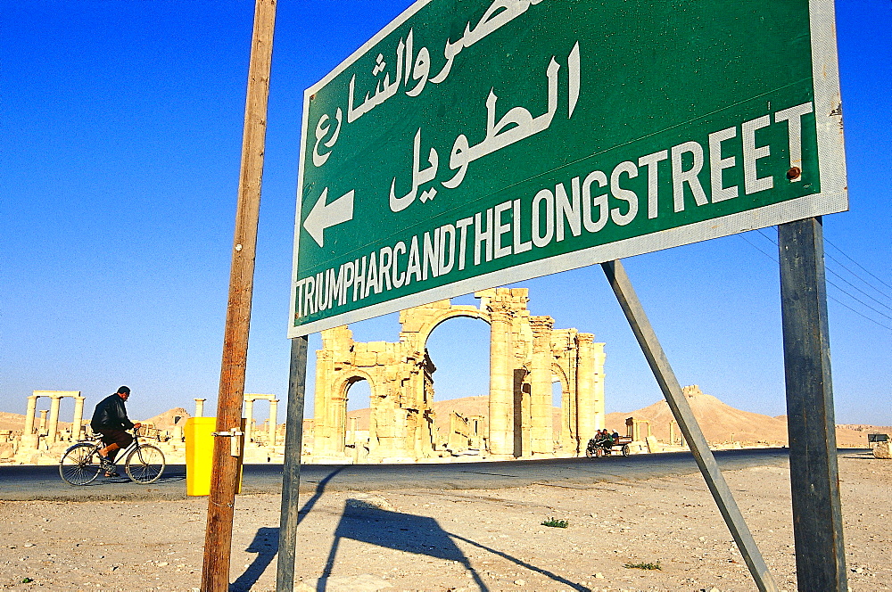 Syria, West Desert, Ruins Of The Ancient City Of Palmyra, Gate Of Roman Cardo Biker And Noticeboard At Fore 