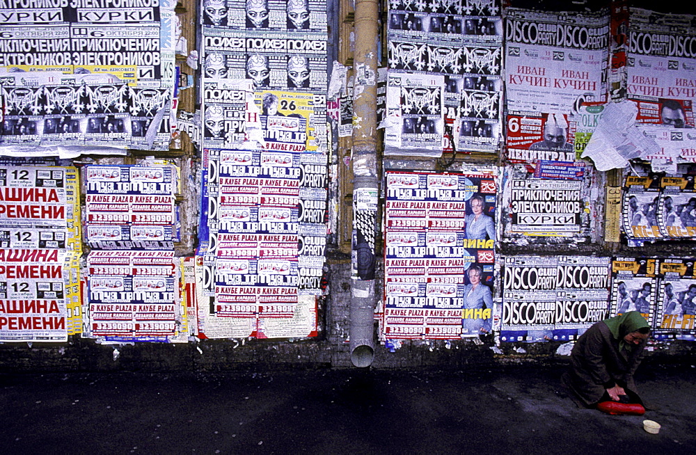 Russia, Saint Petersburg, Newsky Prospekt, Ad Posters On A Wall And Woman Begging 