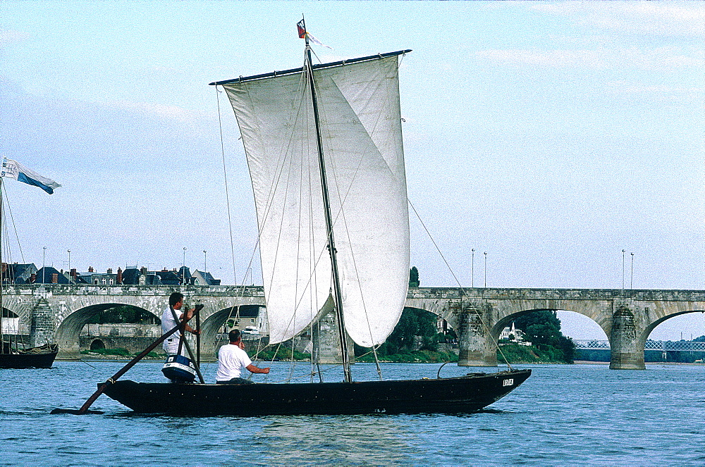 France, Val-De-Loire, Maine-Et-Loire, Saumur, Traditional Sailing Boat On River Loire, Saumur Stone Bridge At Back