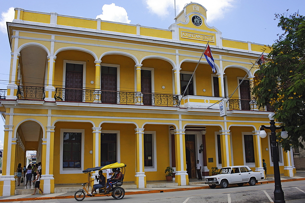 A bici-taxi (bicycle rickshaw) and a popular Russian Lada car in front of the Council House, Marti Square, Ciego de Cvila, Cuba, West Indies, Central America