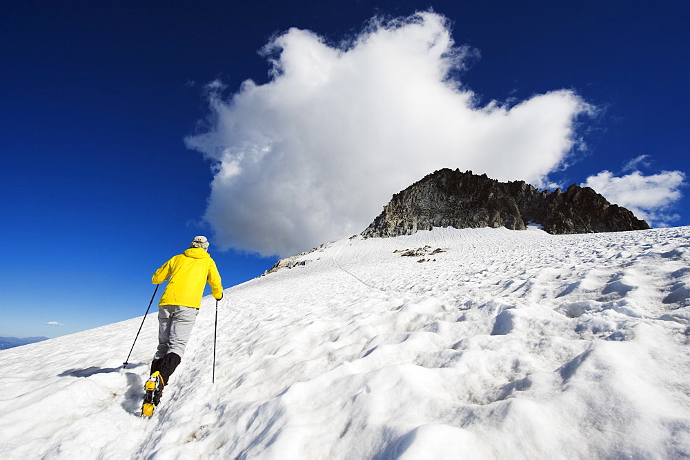 A climber walking up a snowfield, Pico de Aneto, at 3404m the highest peak in the Pyrenees, Spain, Europe