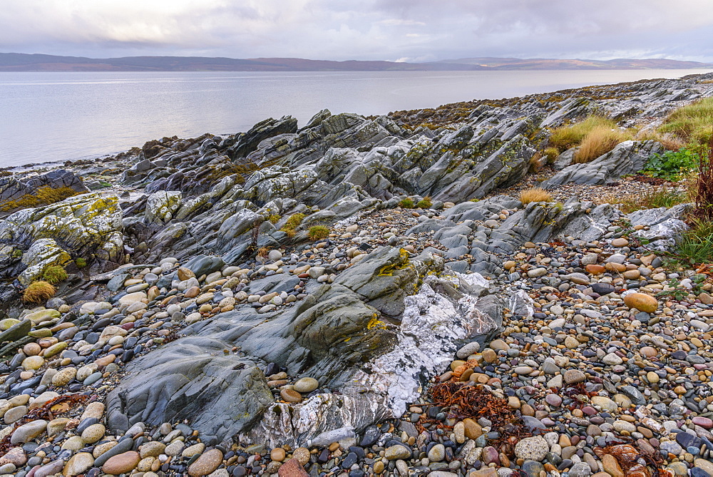 Rocky shore near Pirnmill looking out across the Kilbrannan Sound to Mull of Kintyre, Isle of Arran, North Ayrshire, Scotland, United Kingdom, Europe