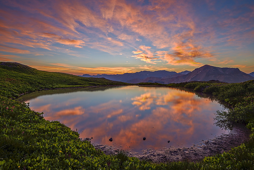 Orange clouds at dawn over a tarn, San Juan National Forest, Colorado, United States of America, North America