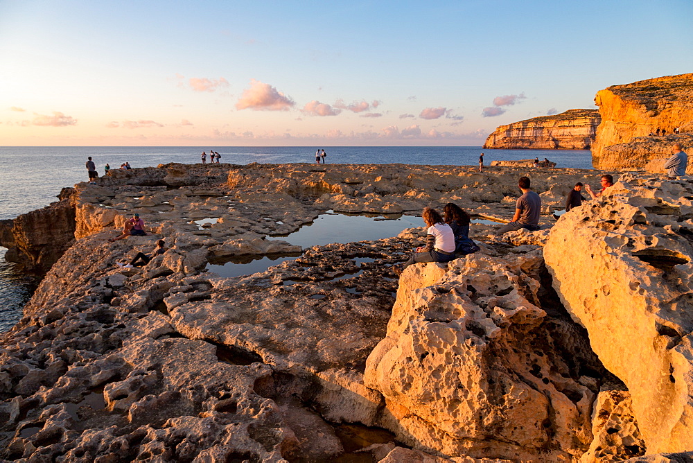 People enjoying sunset at Dwejra Bay on the rugged Gozo coast, Malta, Mediterranean, Europe