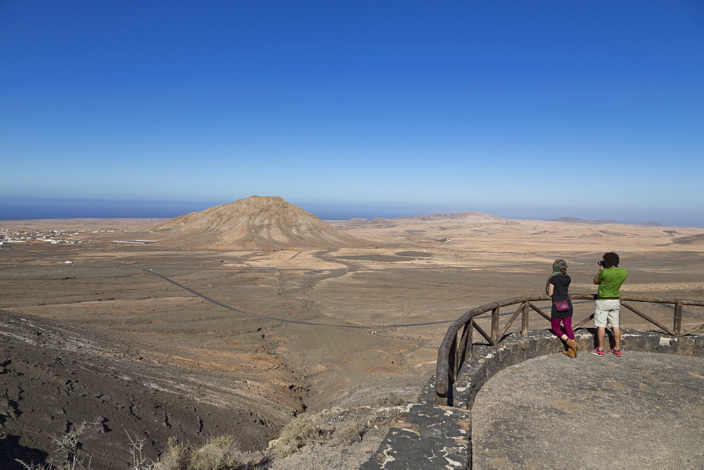 Two people at Mirador de Vallebron looking towards Tindaya volcano on the island of Fuerteventura, Canary Islands, Spain, Atlantic, Europe