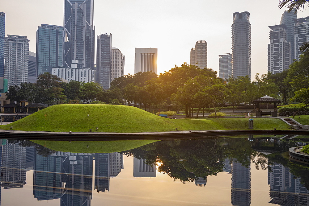 Kuala Lumpur skyline reflected in a still pond in KLCC Park at sunrise, Kuala Lumpur, Malaysia, Southeast Asia, Asia