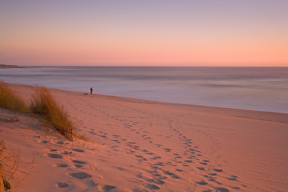 Lone fisherman on beach at sunset, Portugal, Europe