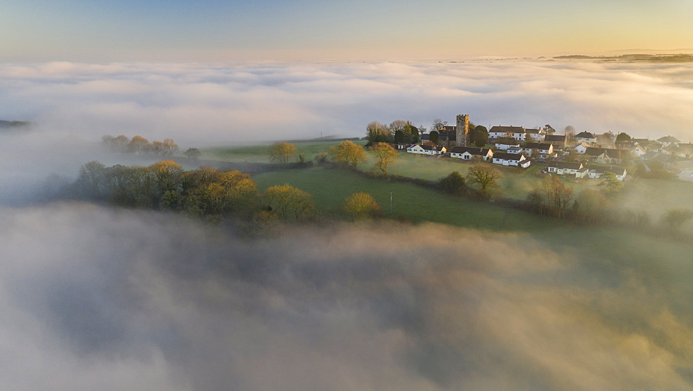 Aerial view by drone of rural village in evening light in winter, surrounded by fog, Coldridge, Devon, England, United Kingdom, Europe