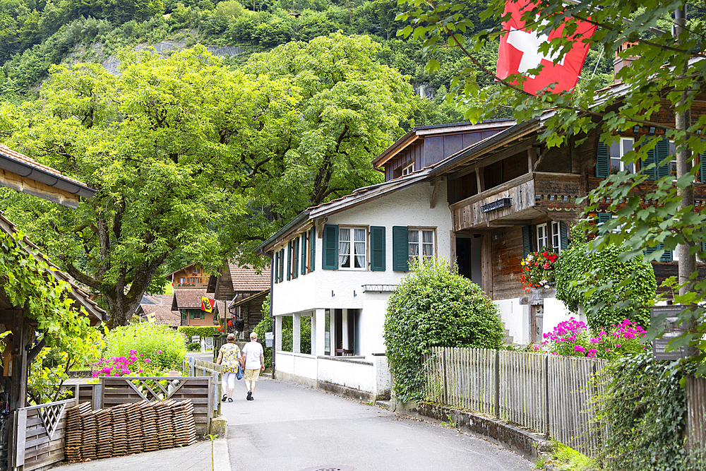 Couple walking past traditional chalets, Iseltwald, Switzerland