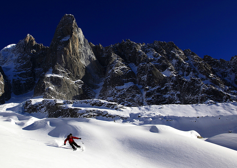 A skier enjoying perfect powder snow on the celebrated Pas de Chevre off-piste run, with the Dru in the background, Chamonix Valley, Chamonix, Haute Savoie, French Alps, France, Europe