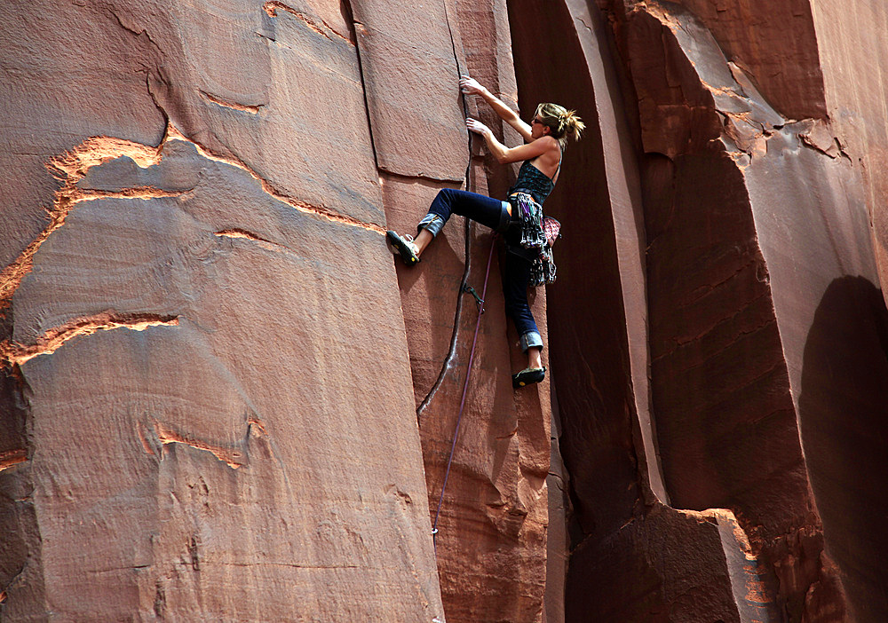 A rock climber tackles an overhanging crack in a sandstone wall on the cliffs of Indian Creek, a famous rock climbing area in Canyonlands National Park, near Moab, Utah, United States of America, North America