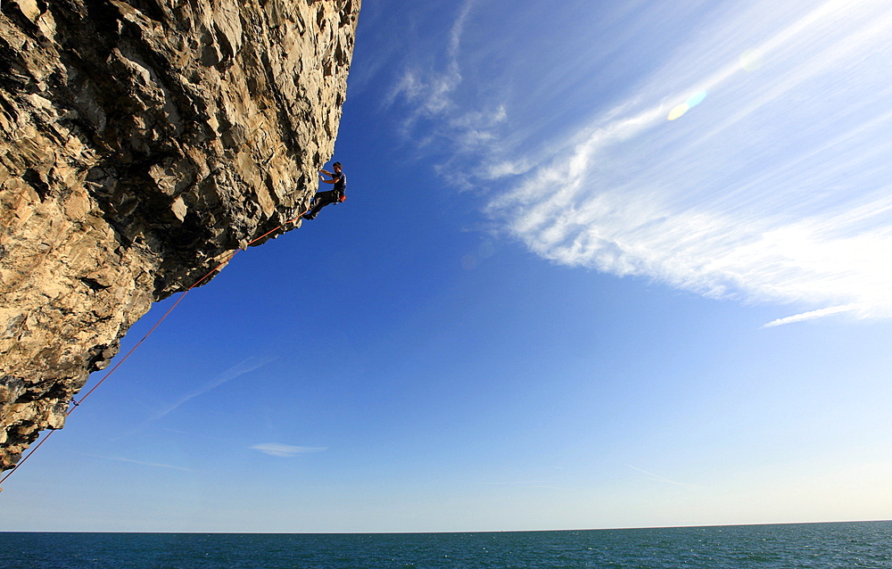 A climber scales cliffs near Swanage, Dorset, England, United Kingdom, Europe