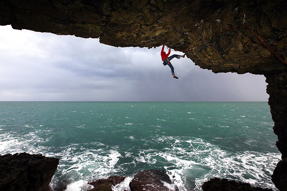 A climber scales cliffs near Swanage, Dorset, England, United Kingdom, Europe