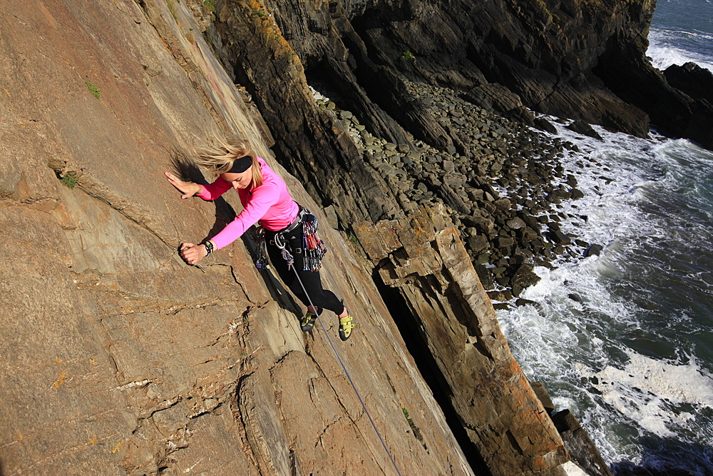 A climber scales cliffs at Baggy Point, Devon, England, United Kingdom, Europe